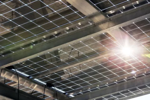 Die Sonne scheint durch ein transparentes Solarmodul, dass als Carport-Dach eingesetzt wird und gleichzeitig Solarstrom produziert.